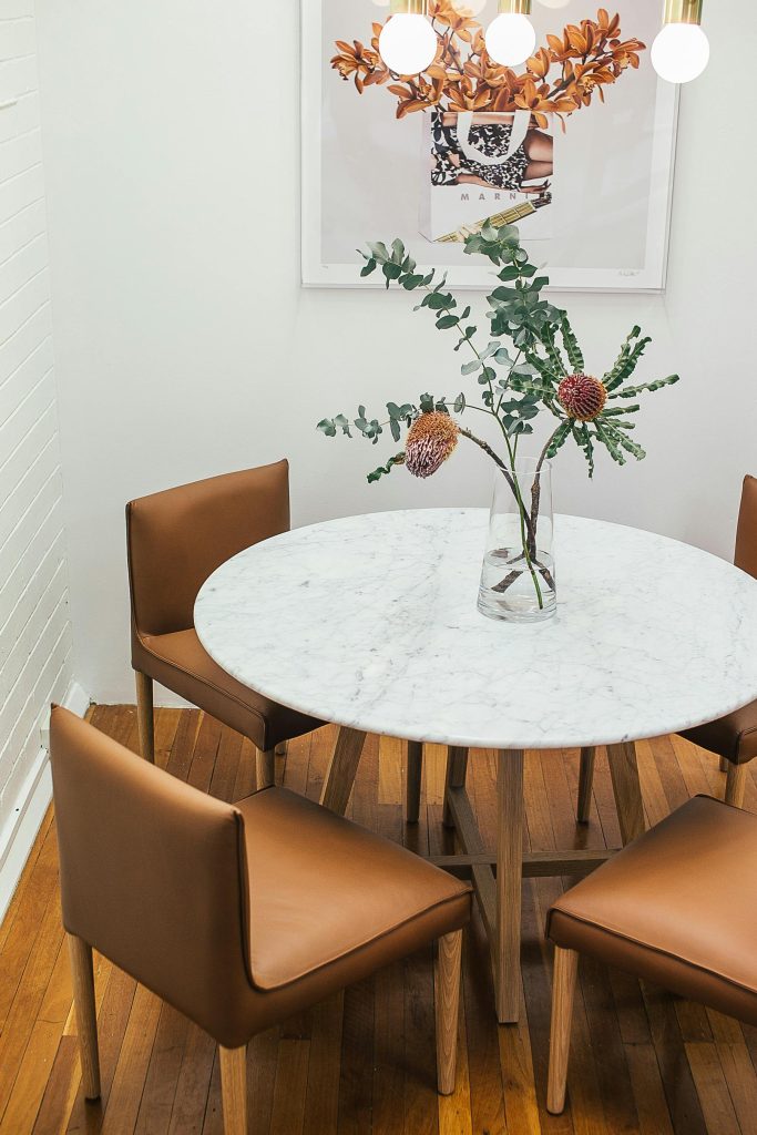 Stylish modern dining room with a marble table, brown chairs, and decorative plants.